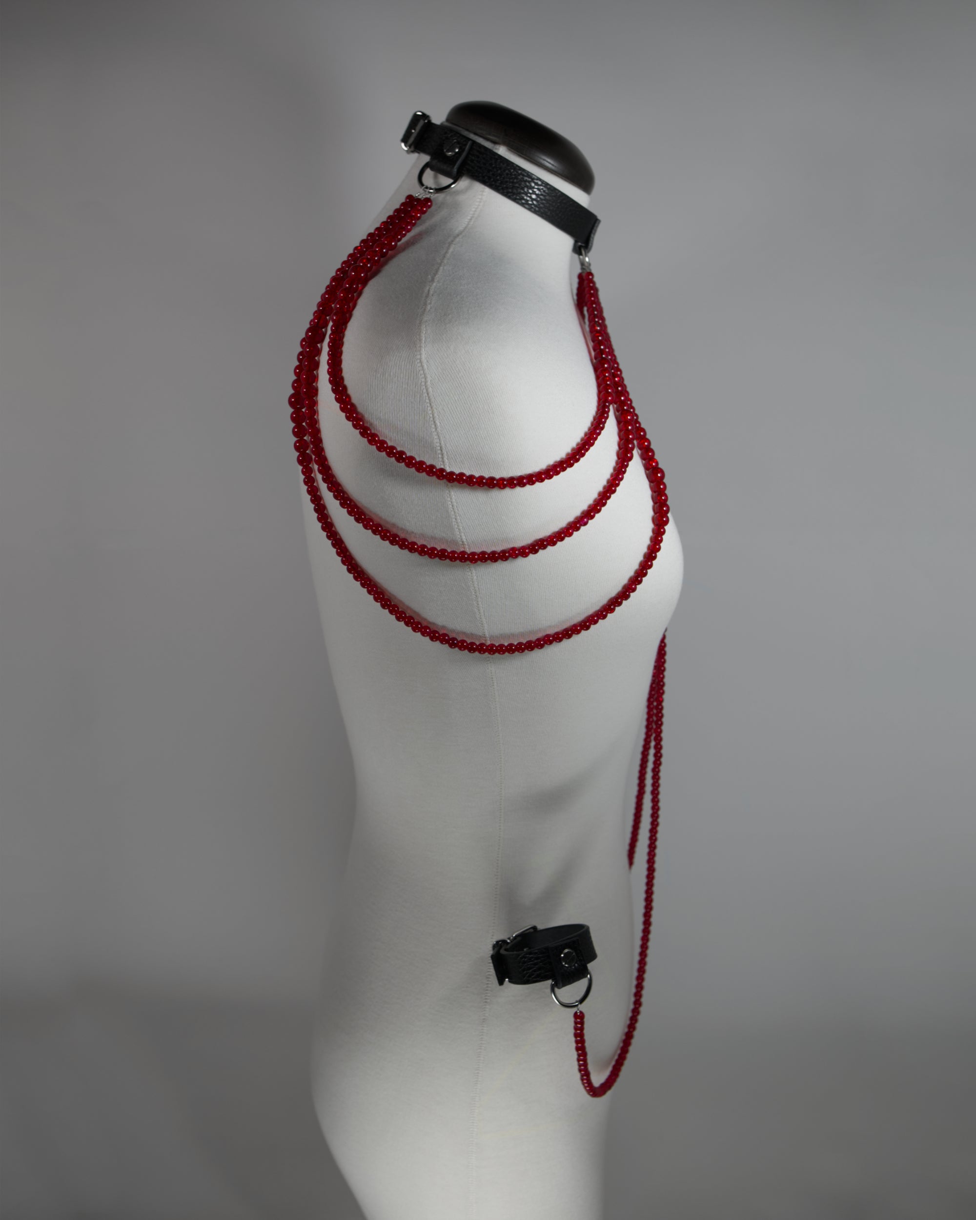 leather choker inspired by persephone with red beads chains draping on the shoulders and cuffs attached to the choker