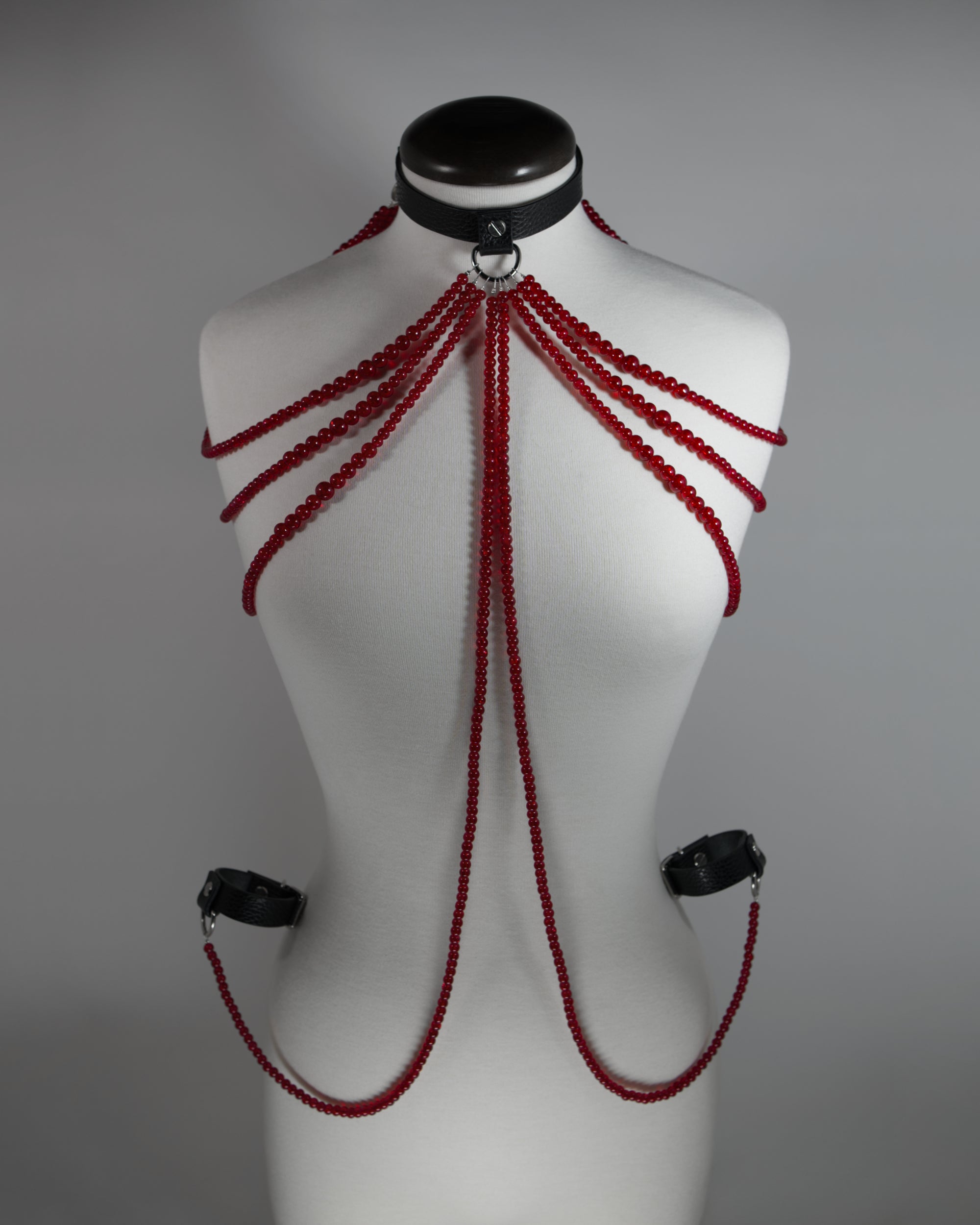 leather choker inspired by persephone with red beads chains draping on the shoulders and cuffs attached to the choker